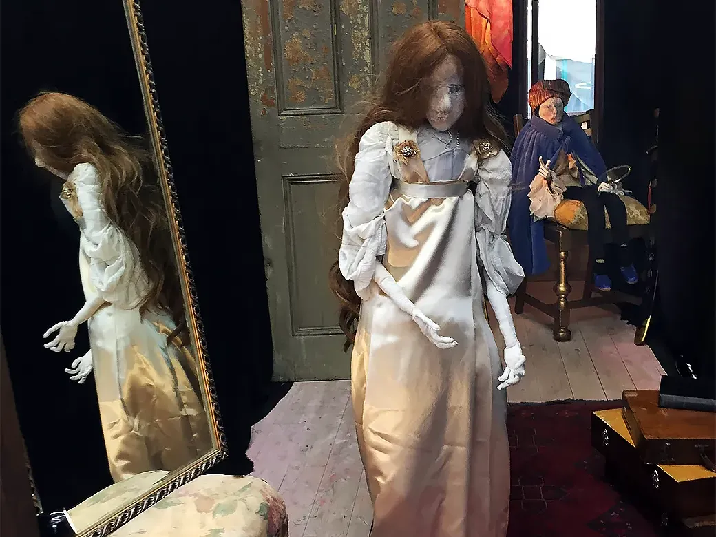Woman sculpture reflected in a mirror and one man in the background.