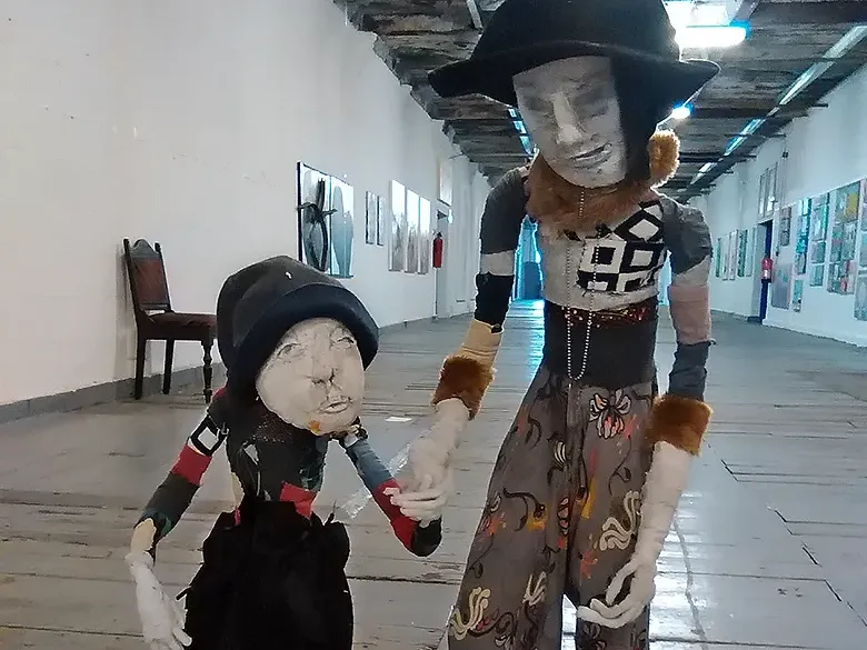 Two boys sculptures holding hands are walking along an industrial corridor.