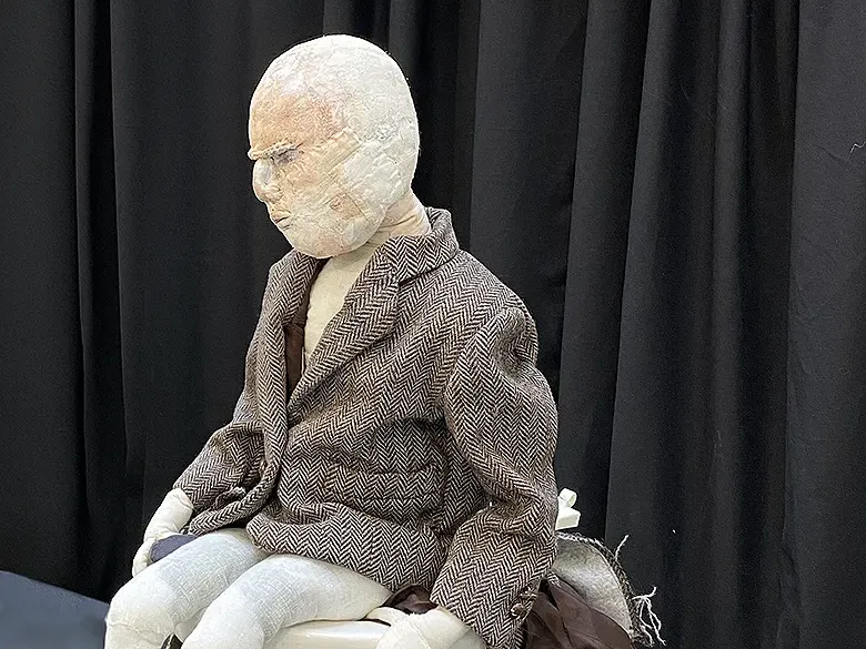 Boy with tweed jacket sitting on a cubicle with overflowing fabrics.