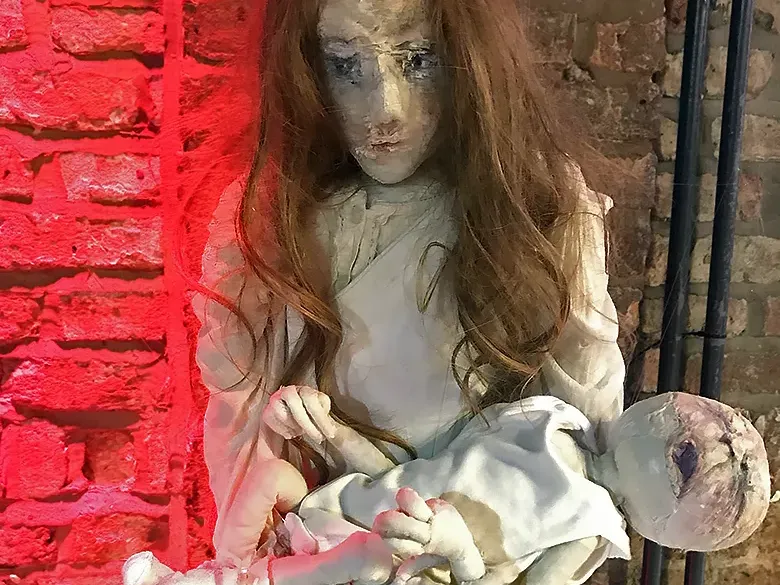 A girl sculpture holding a crying baby.