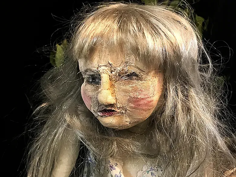 A girl sculpture before a dark background.