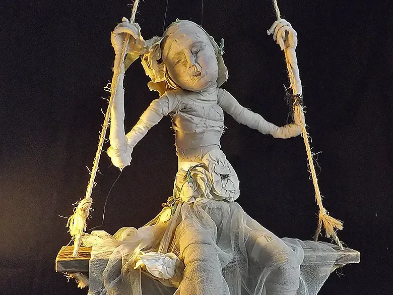 Child sculpture sitting dreamily on a swing.