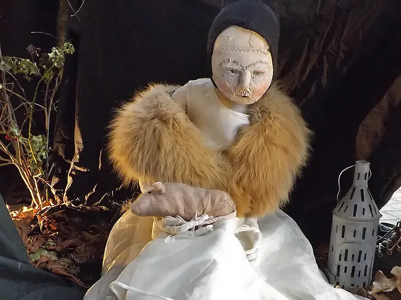 Girl sculpture in white dress and fur stole with an open book on the floor.
