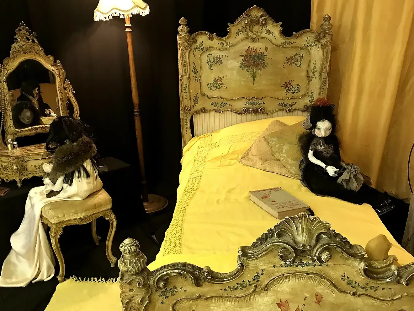 Partial view into a bedroom with dominant yellow colour design with two woman sculptures.
